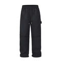 Men's baggy paratrooper pants in black with elastic waist and drawstring, side view on model