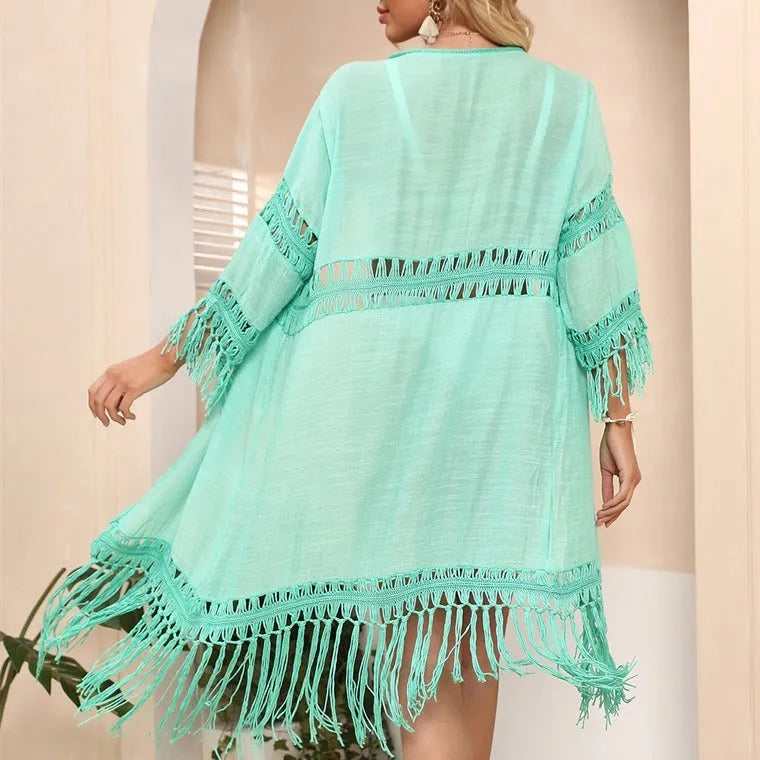 Yellow hand-crocheted women's beach cardigan with tassel trim on a hanger