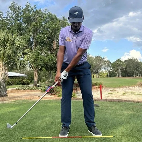 Plastic golf swing plane training aid simulator on a green background.