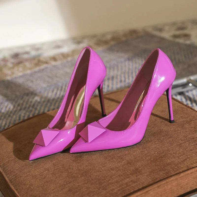 Pink patent leather women's stiletto heels with pointed toes and rivet buckle detailing