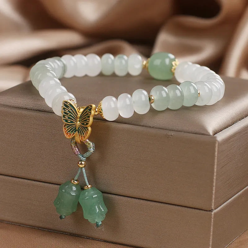 Tian Shan Cui green crystal abacus beads bracelet with butterfly tassel, pearls, and rhinestones on white background