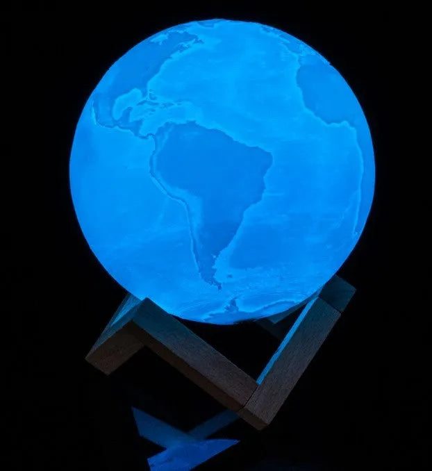 3D printed white moon lamp on a wooden stand with a glowing centre.