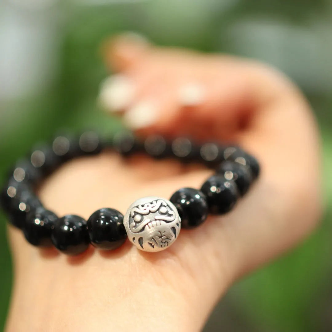 Close-up of a black agate and sterling silver bracelet with 10mm beads and Chinese style design.