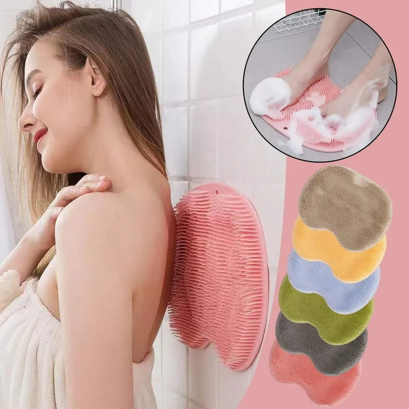 Orange massage bath brush with silicone bristles and suction cup base on a shower floor
