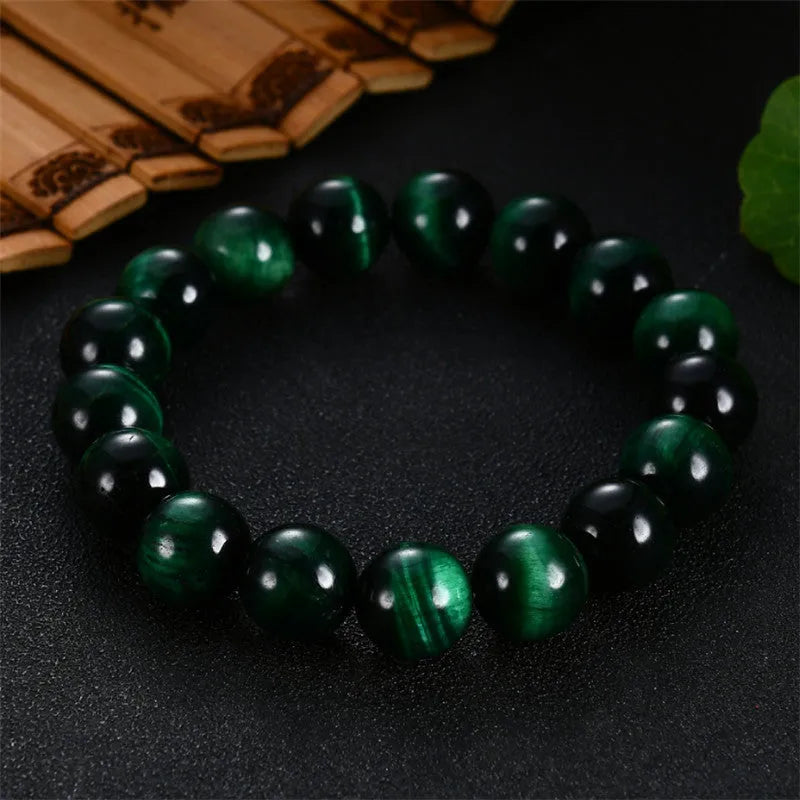 Green tiger eye stone bracelet with geometric polished beads on a wrist.