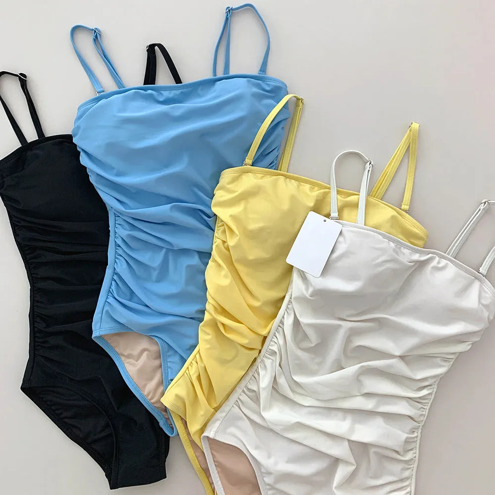 Sling style one-piece swimsuit with belly pleats in solid colour options