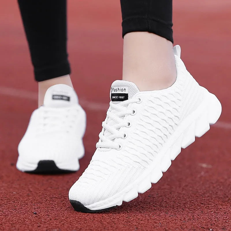 Women's running shoes in black, pink, and white with a fly weave upper and durable outsole.
