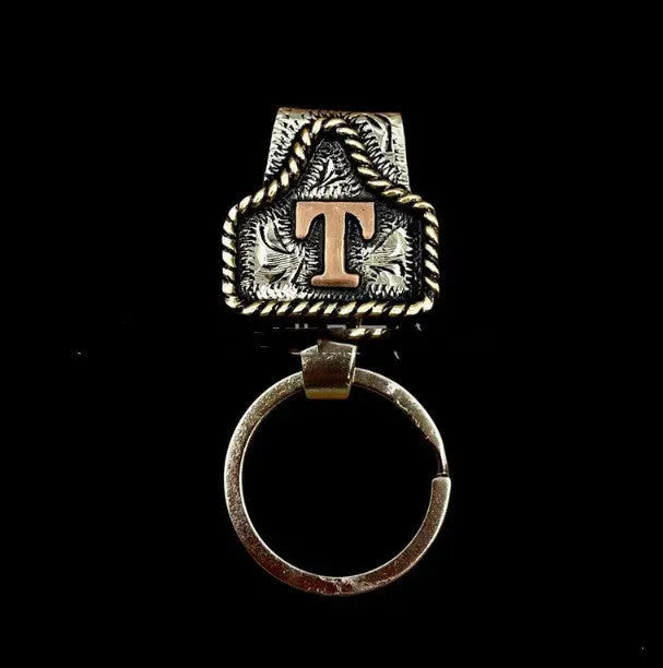 Handmade metal keychain with a cow motif, shown in one of 26 available colours.