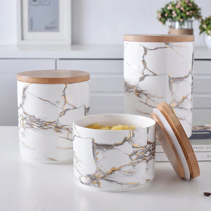 Three marbled ceramic jars with bamboo lids in large, medium and small sizes on a kitchen counter