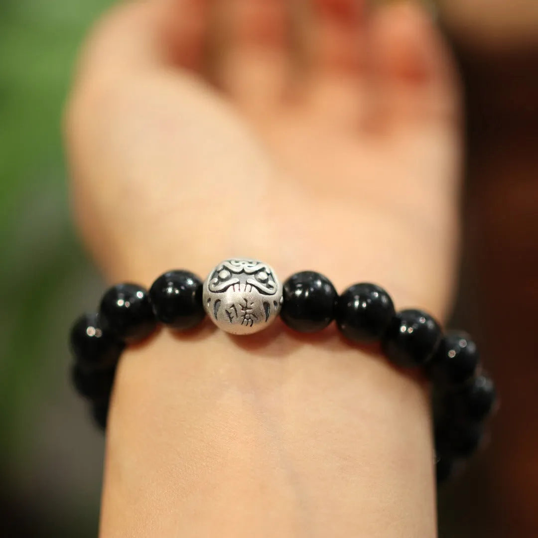 Close-up of a black agate and sterling silver bracelet with 10mm beads and Chinese style design.