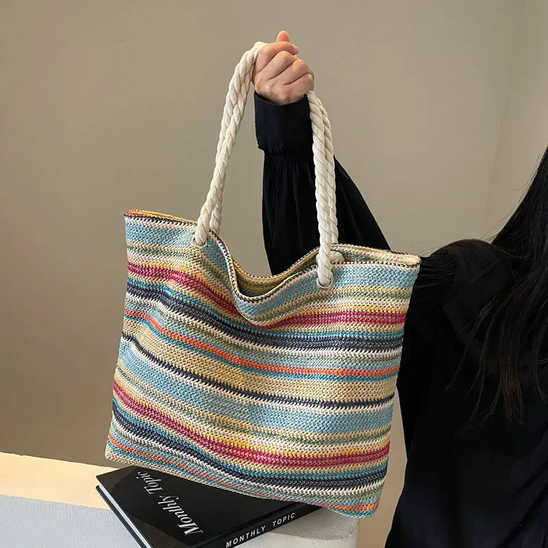 Blue woven shoulder bag with straw and nylon construction showing adjustable straps and textured exterior