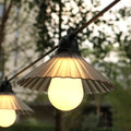 Outdoor LED string lights with flower-shaped globes in four colours, hanging in a garden.