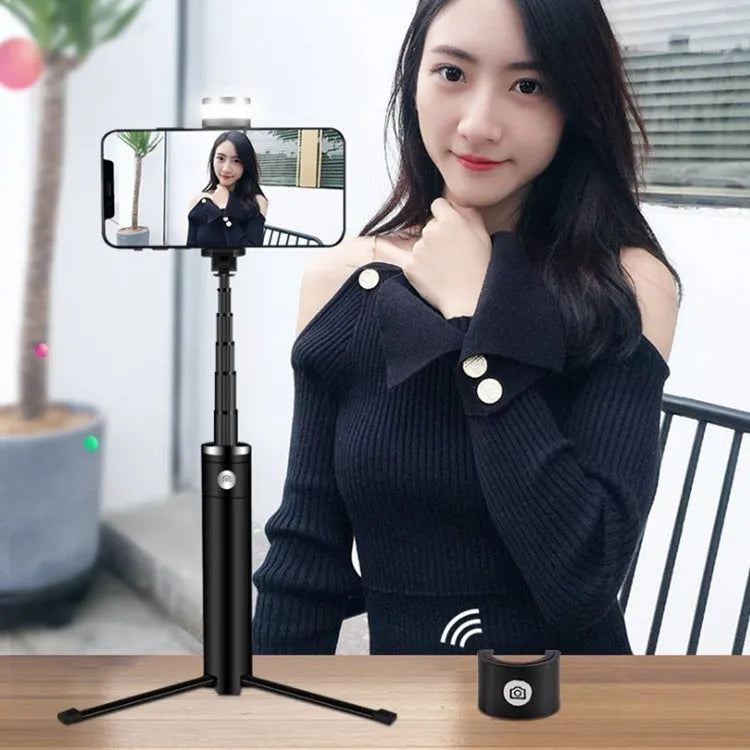 Black 7-in-1 desktop lamp selfie stick with LED lights, Bluetooth remote, and built-in tripod on a table