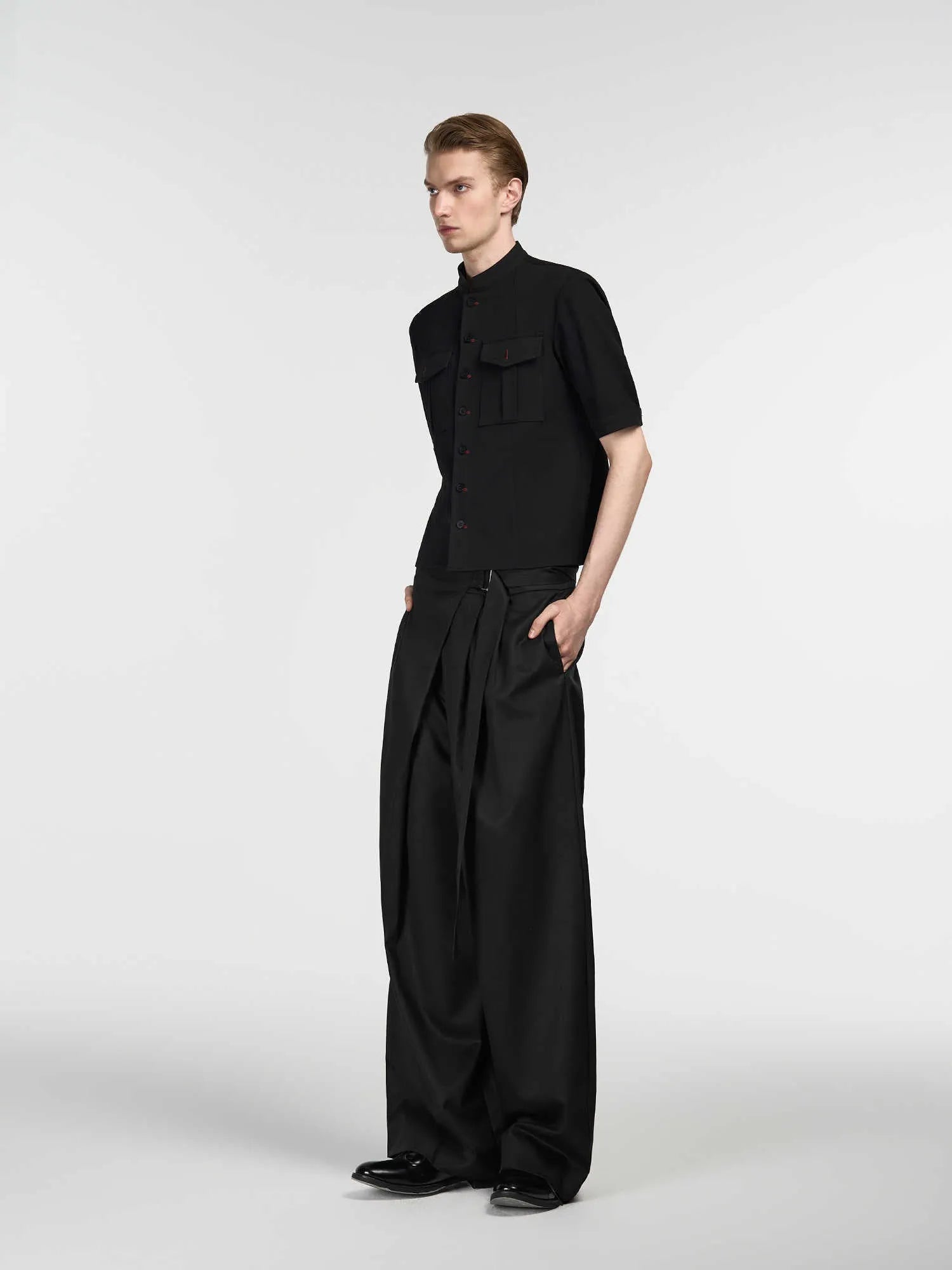 Black straight-leg trousers with single pleat front and adjustable waistband on hanger