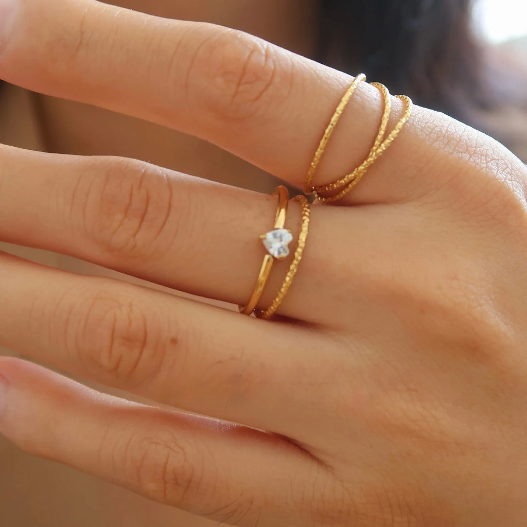 Golden electroplated stainless steel ring showing heart shape and oval charm design on female hand