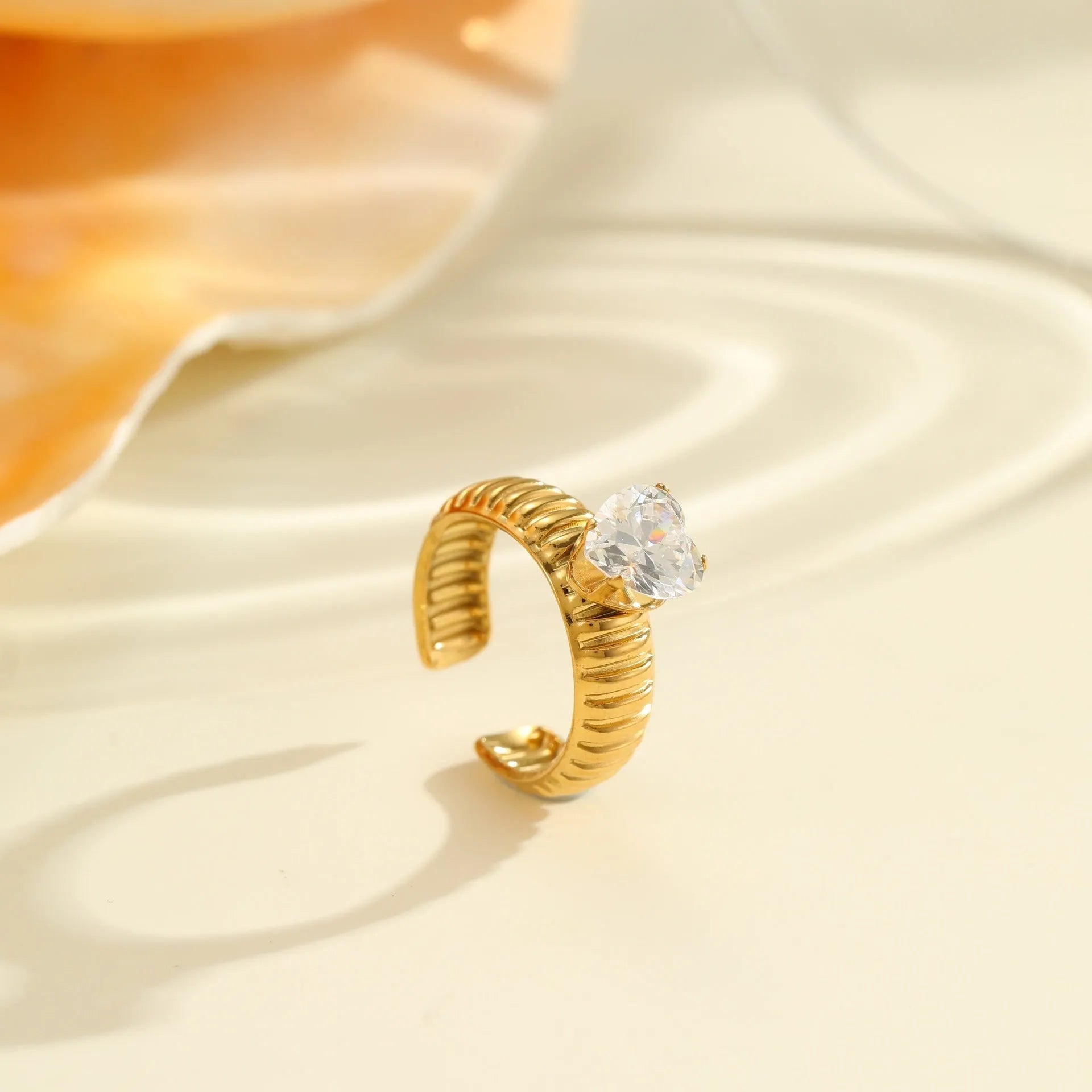 Gold electroplated geometric stainless steel ring with inlaid zircon stones on a finger, showing open mouth design.