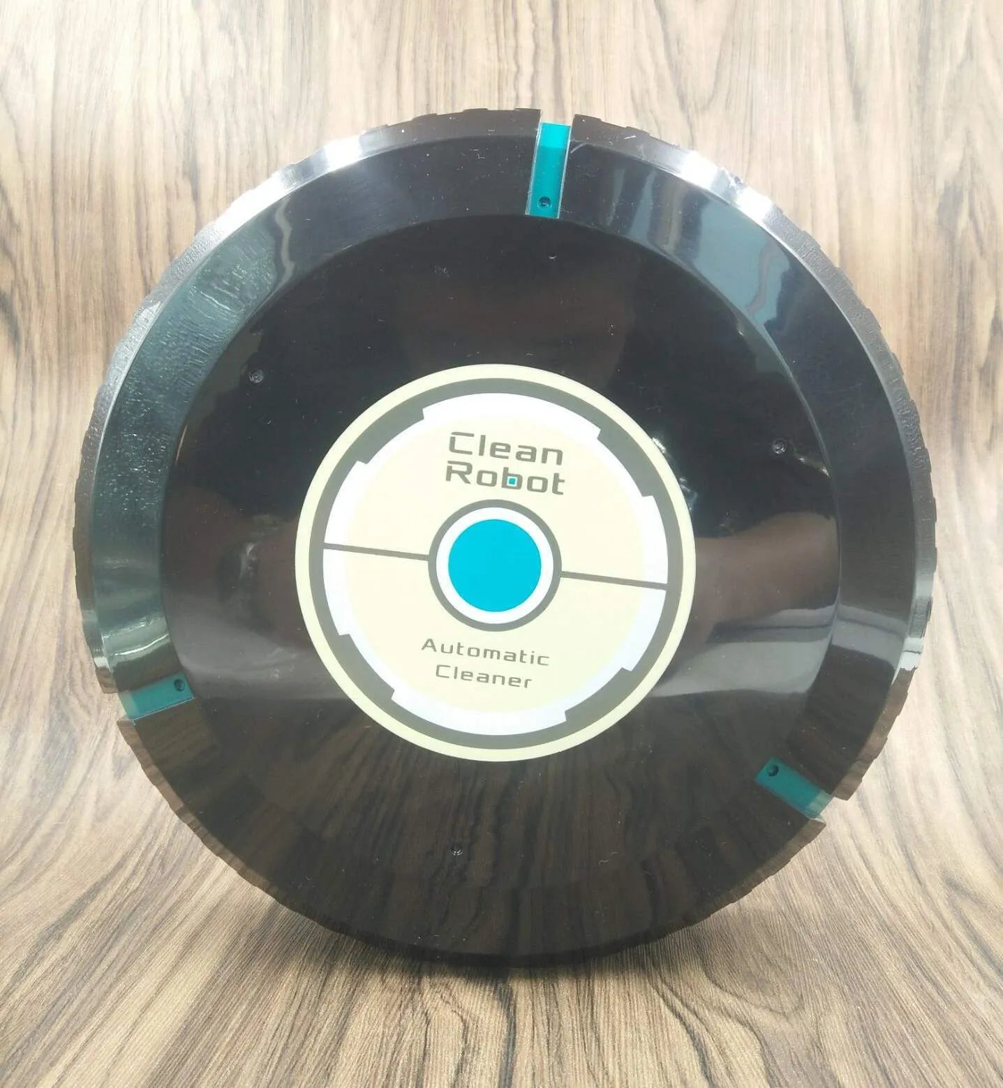 AC household automatic sweeping robot in black on a wooden floor.