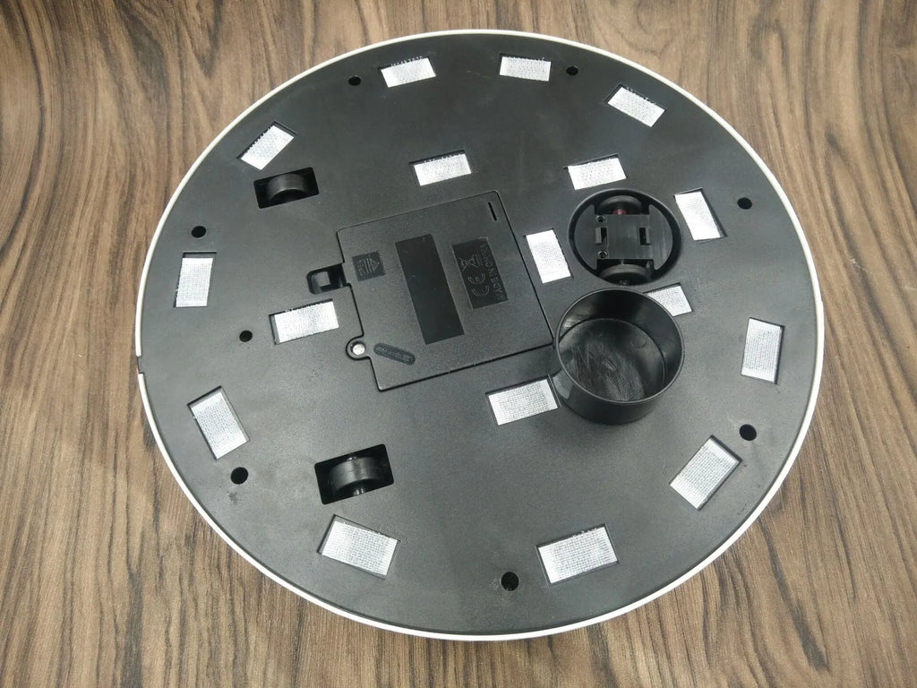 AC household automatic sweeping robot in black on a wooden floor.
