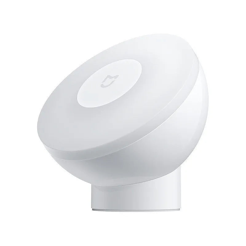 White modern bedside table lamp with human body induction and Bluetooth on a wooden nightstand.