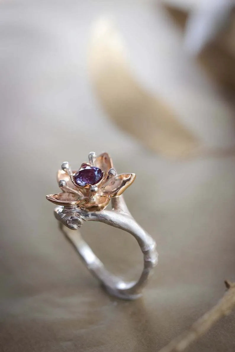 Silver two-tone women's ring with a geometric floral design on a finger.
