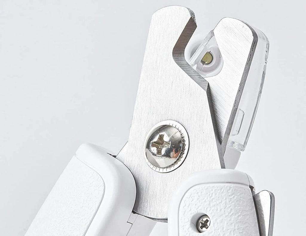 White pet nail clippers with LED light, transparent guard, and a separate nail file on a plain background.