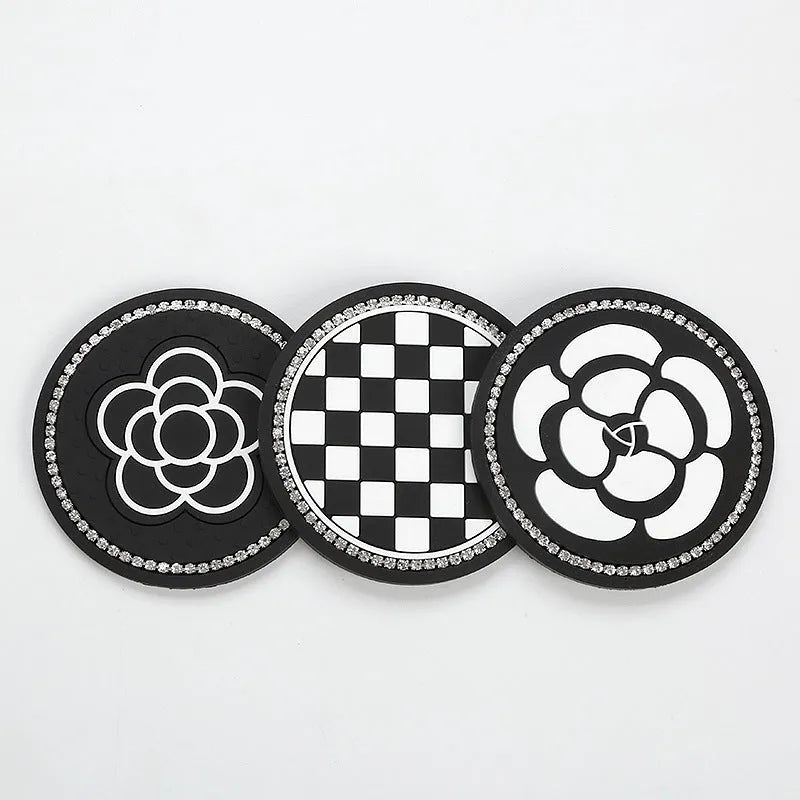 Plastic car water cup mat in black and white checkerboard with drill detailing on a non-slip surface for cup holder use