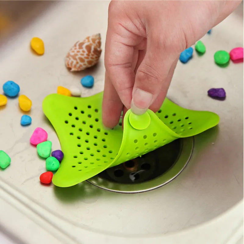 Three silicone starfish sink drain strainers in white, blue, and green with suction cups on bottom