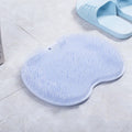 Orange massage bath brush with silicone bristles and suction cup base on a shower floor
