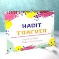 Habit tracking journal open showing internal pages with 21x28cm dimensions and coloured cover