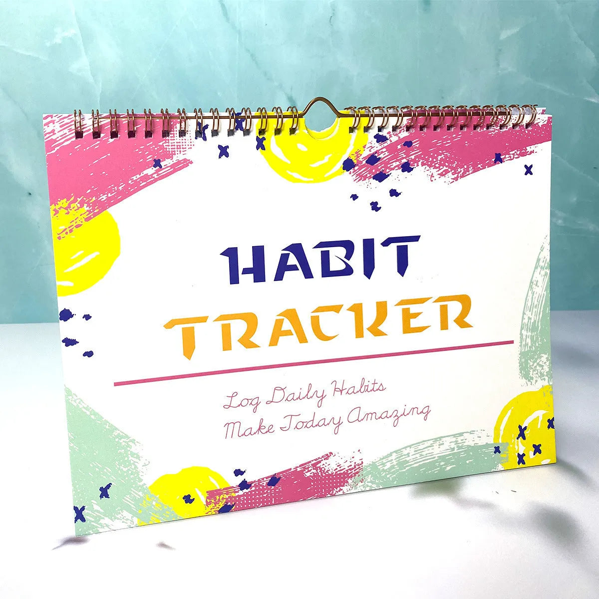 Habit tracking journal open showing internal pages with 21x28cm dimensions and coloured cover