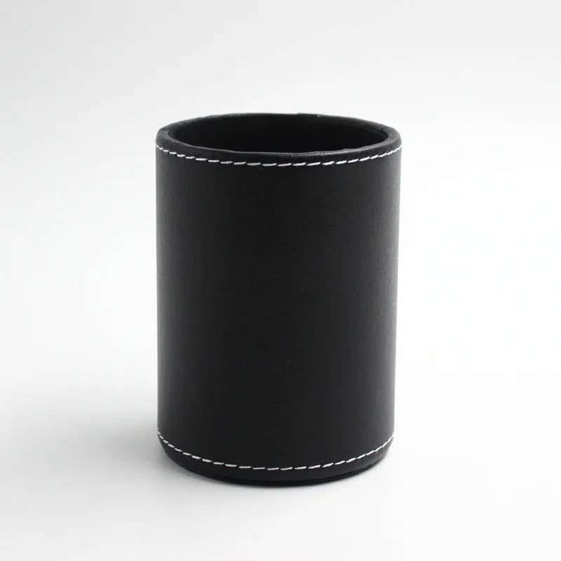 Round black leather pen holder on desk with pens