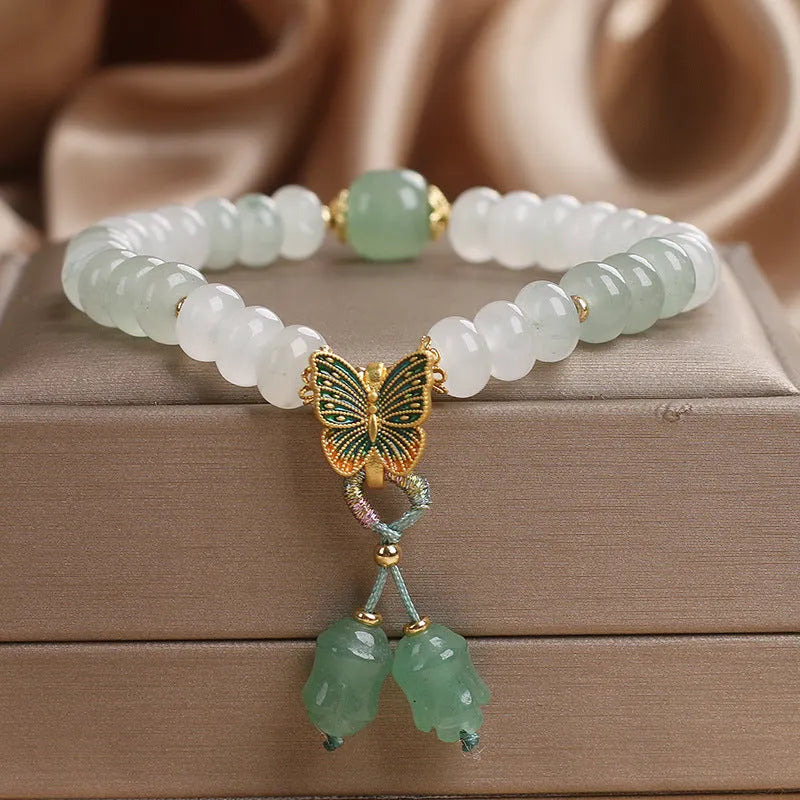 Tian Shan Cui green crystal abacus beads bracelet with butterfly tassel, pearls, and rhinestones on white background