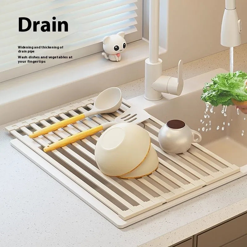 Milky white tri-fold stainless steel kitchen draining rack shown unfolded next to a sink.