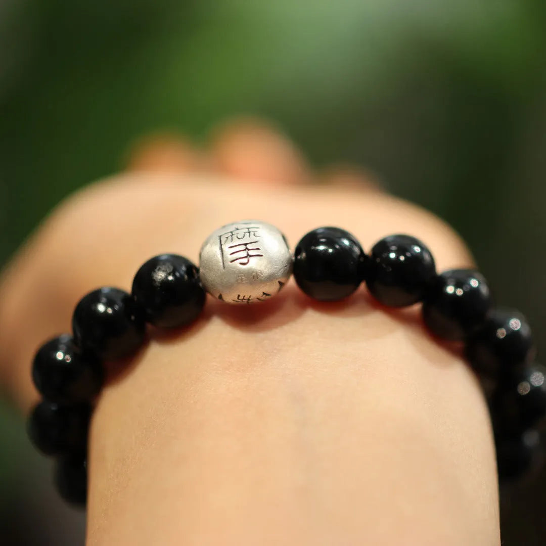 Close-up of a black agate and sterling silver bracelet with 10mm beads and Chinese style design.