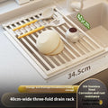 Milky white tri-fold stainless steel kitchen draining rack shown unfolded next to a sink.