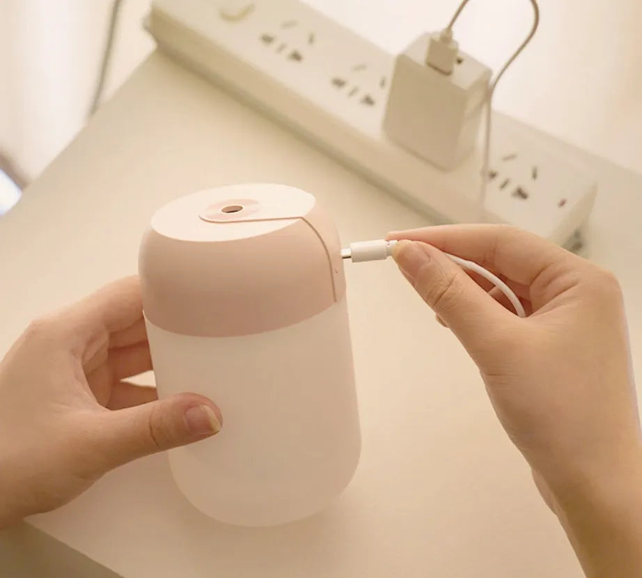 Small white cylindrical USB humidifier with charging cable on table