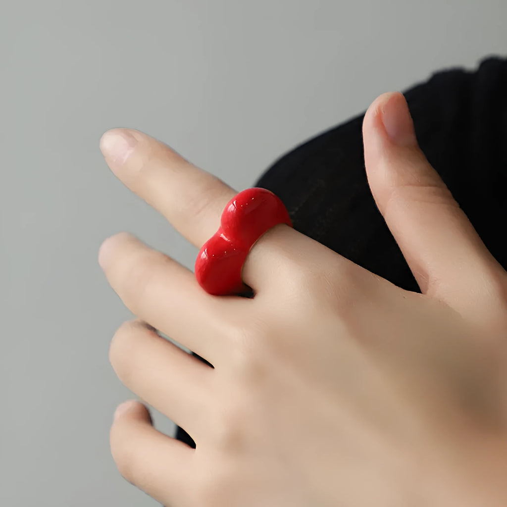 Three-dimensional heart-shaped enamel fashion ring in red, shown from the side.
