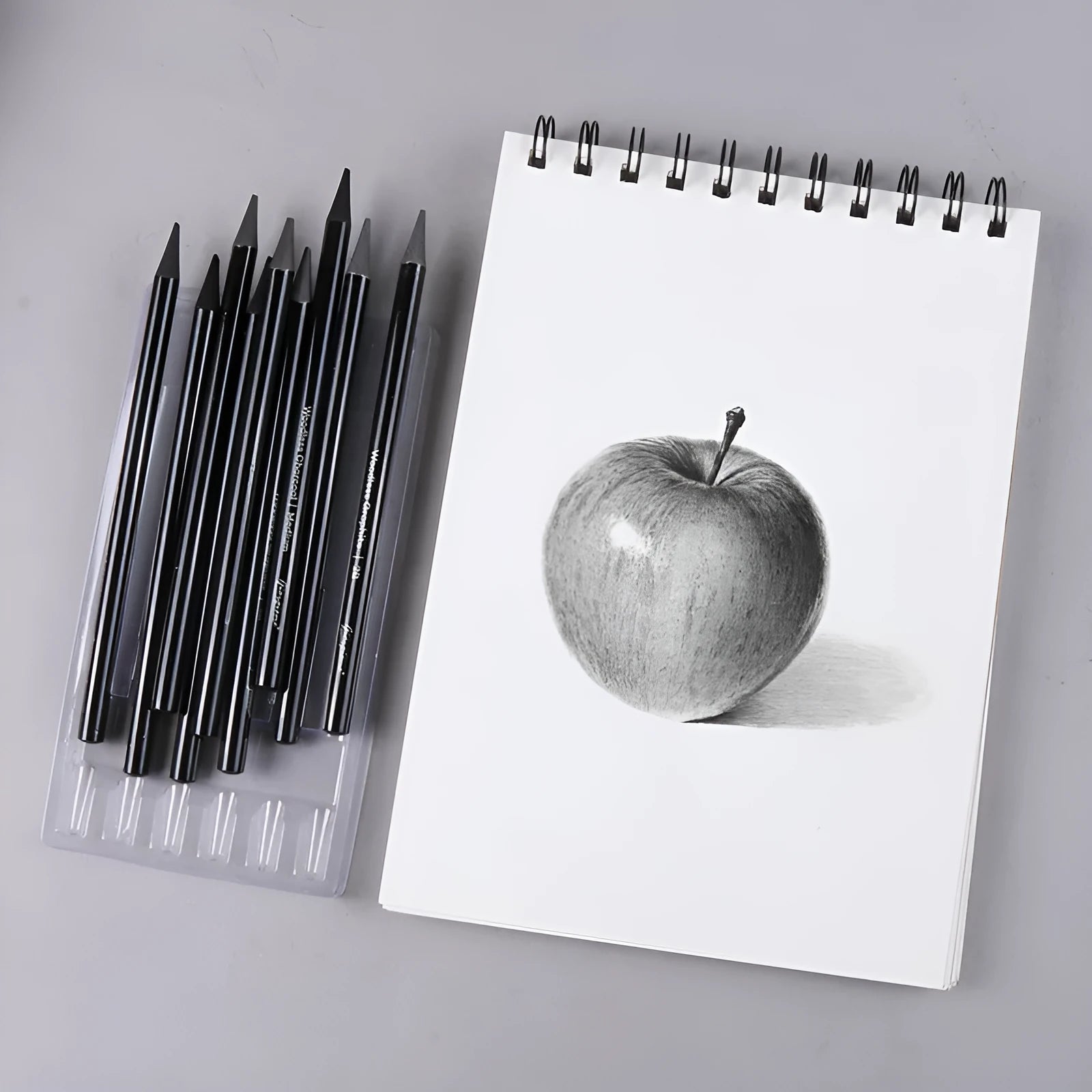 Set of nine graphite and carbonised wooden drawing pencils displayed on a suction card packaging.