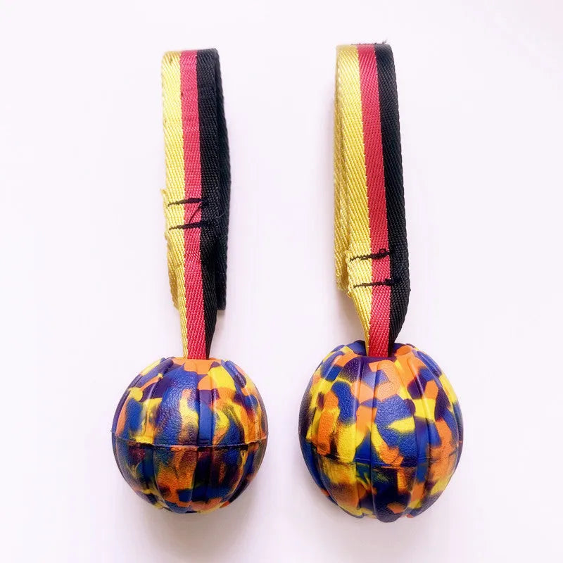 A floating EVA foam dog tetherball with a string attached, shown in camouflage colour next to a yellow one.