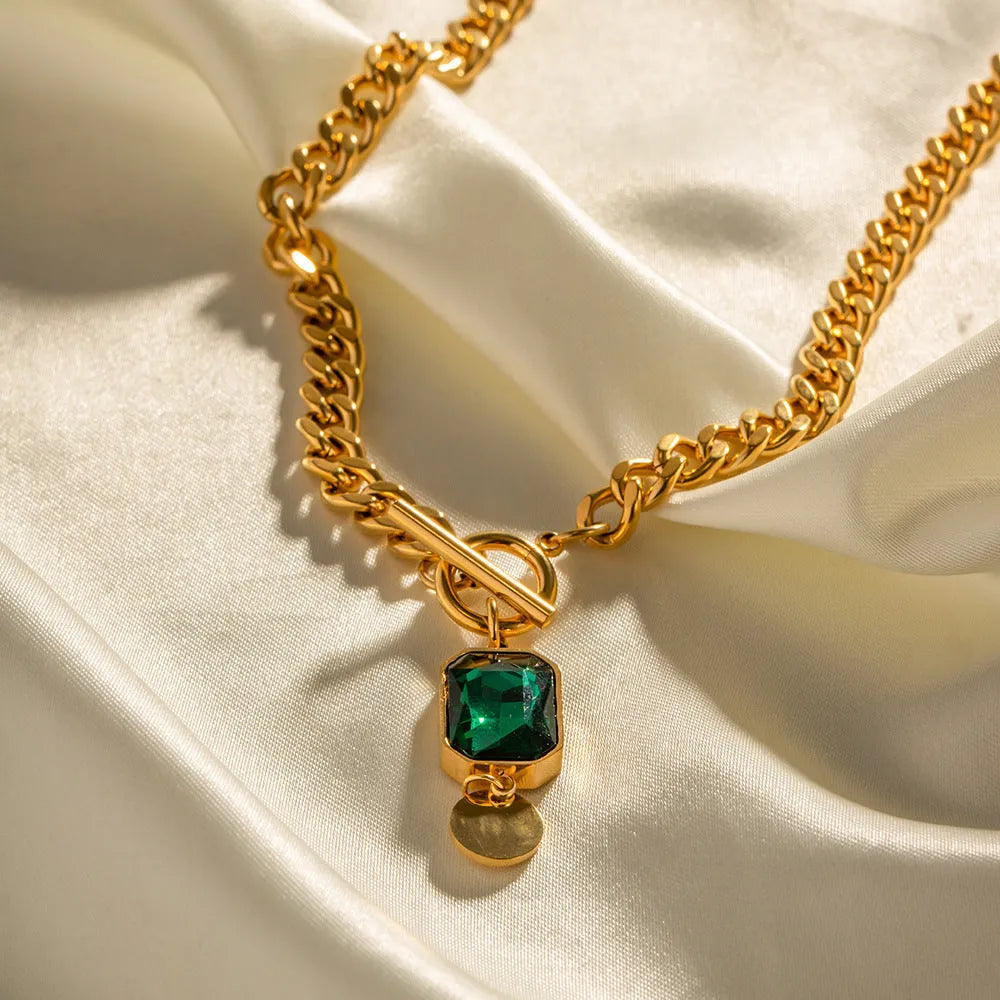 Gold titanium steel necklace with round emerald green zircon pendant on a Cuban link chain.