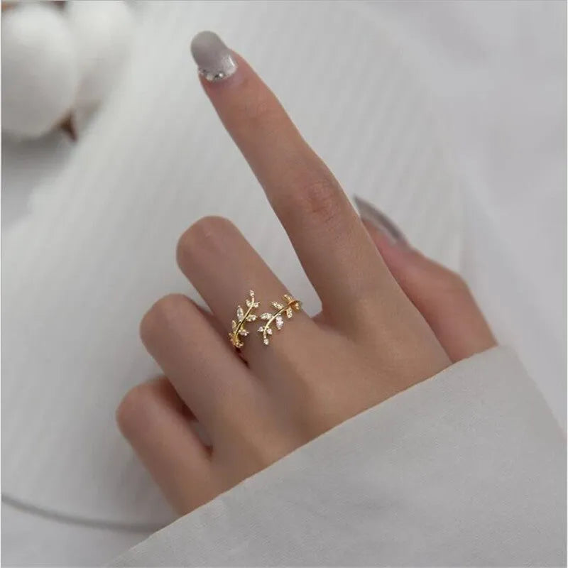 Gold and silver women's branch leaf fashion ring with geometric design on a plain background.