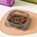 Blue plastic slow-feeder dog bowl on a wooden floor.