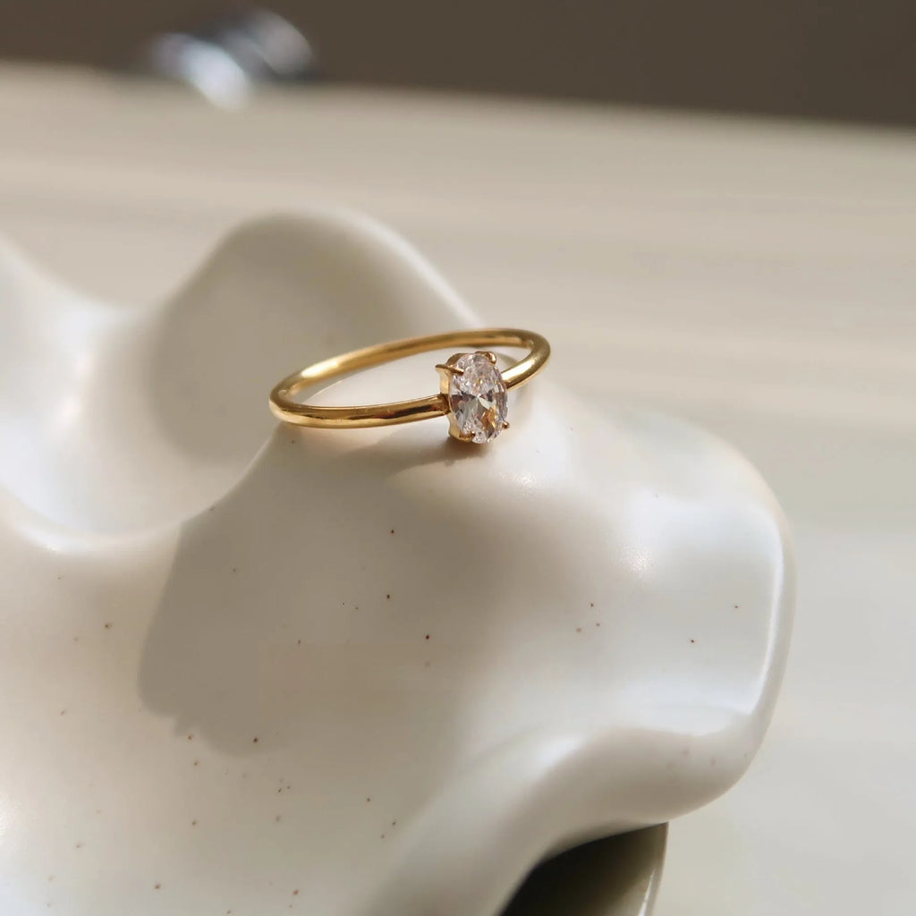 Golden electroplated stainless steel ring showing heart shape and oval charm design on female hand