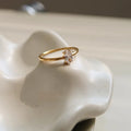 Golden electroplated stainless steel ring showing heart shape and oval charm design on female hand