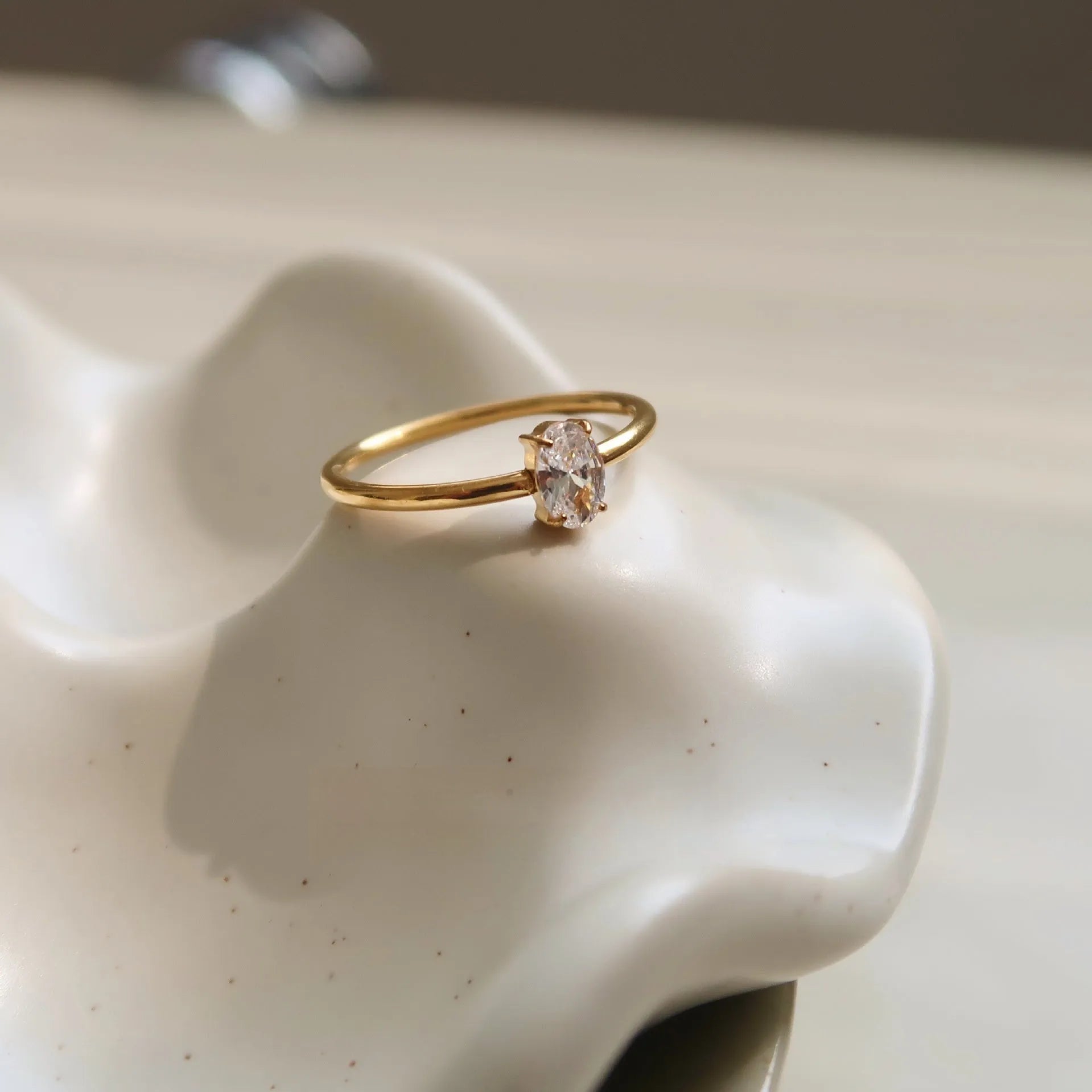 Golden electroplated stainless steel ring showing heart shape and oval charm design on female hand
