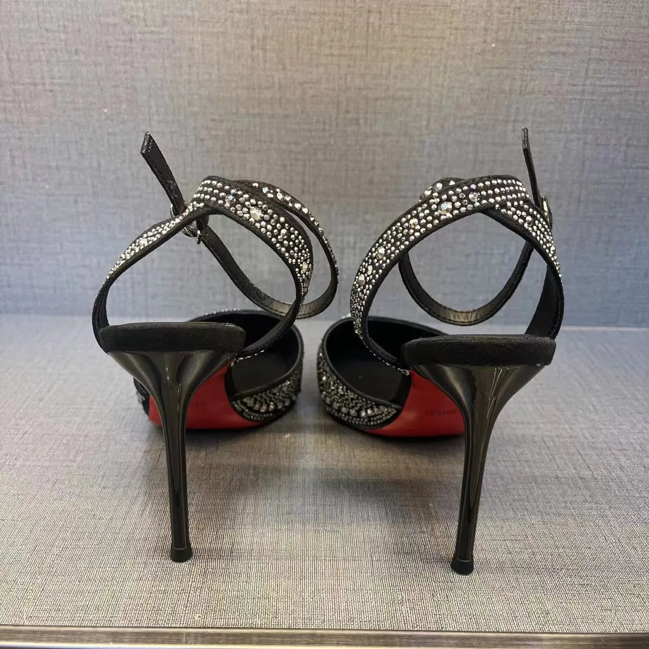 Women's black hollow high heel with stiletto heel, pointed toe, and red sole on a plain background.