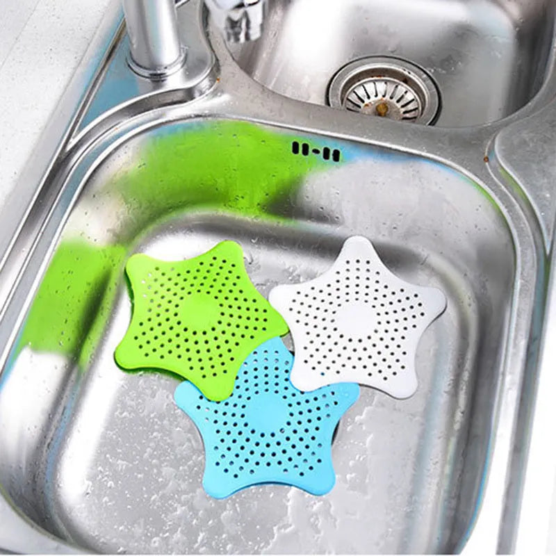 Three silicone starfish sink drain strainers in white, blue, and green with suction cups on bottom