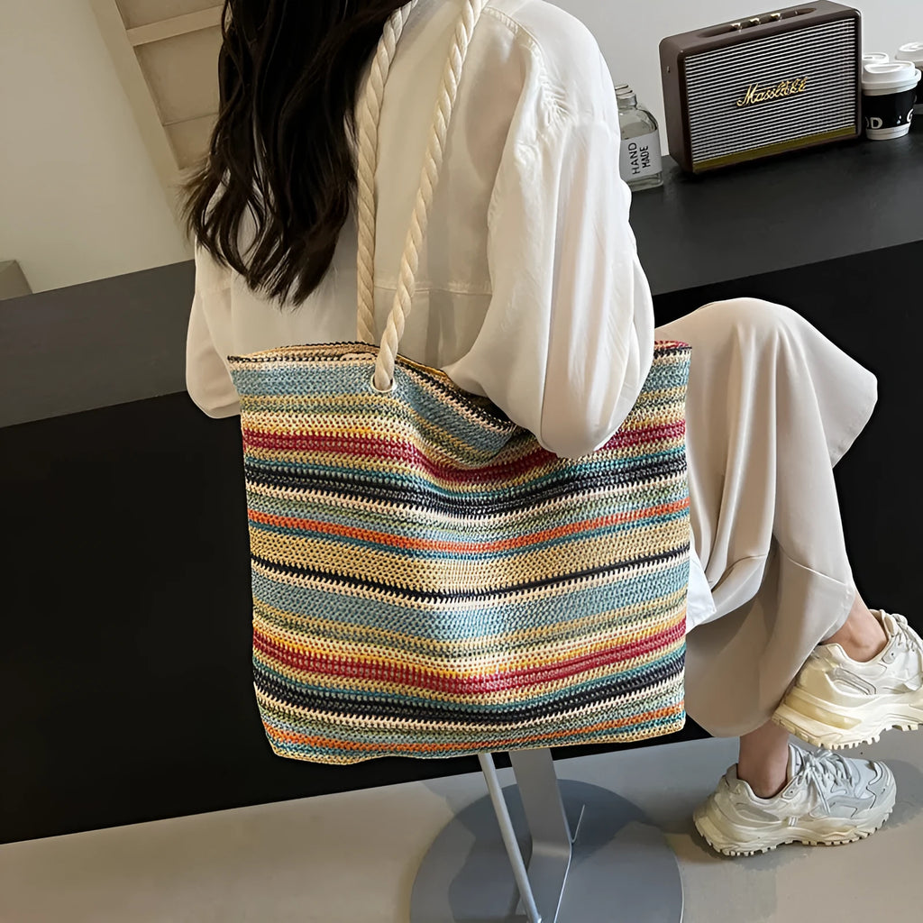 Blue woven shoulder bag with straw and nylon construction showing adjustable straps and textured exterior