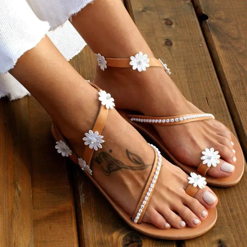 Brown women's sandals with flat rubber soles and decorative flower accents on the upper