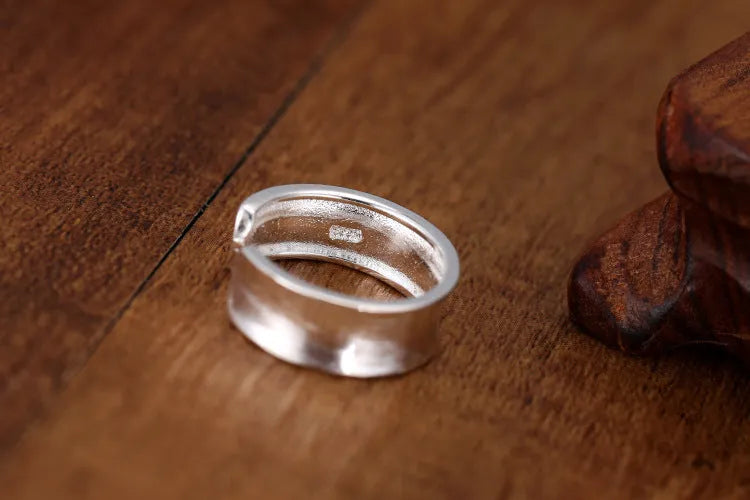 Geometric open ring in frosted sterling silver on a neutral background, showing adjustable opening.